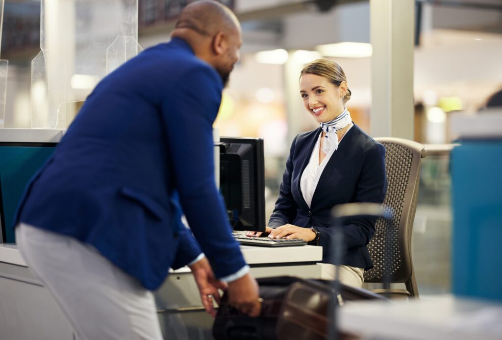 Black man, airport reception and security check with woman, concierge and help desk in lobby with l